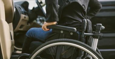 Un homme dans un fauteuil roulant s'apprête à s'installer au volant d'une voiture